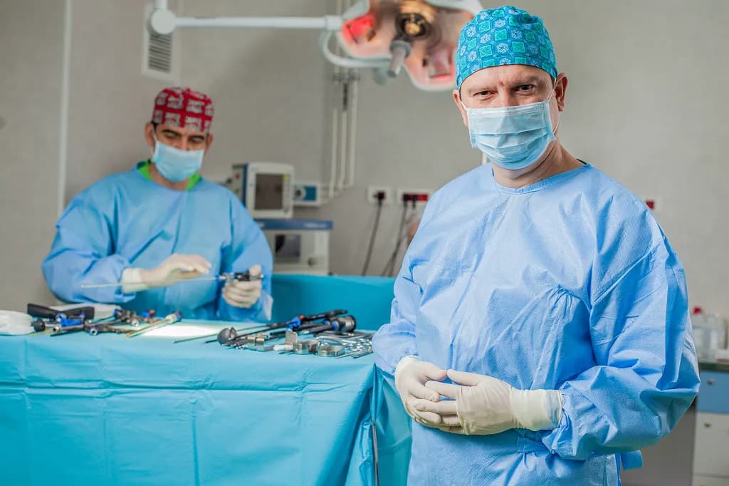 Dr. Dan Raica în sala de operație, lângă masa cu instrumentar chirurgical