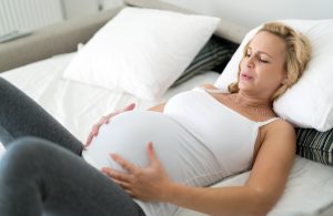 Pregnant blonde woman having big contractions at home